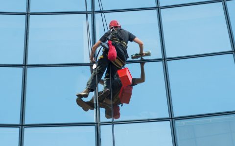 portrait of worker washing windows of the modern building.